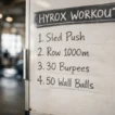 HYROX workout station board showing key exercises to train for a HYROX race
