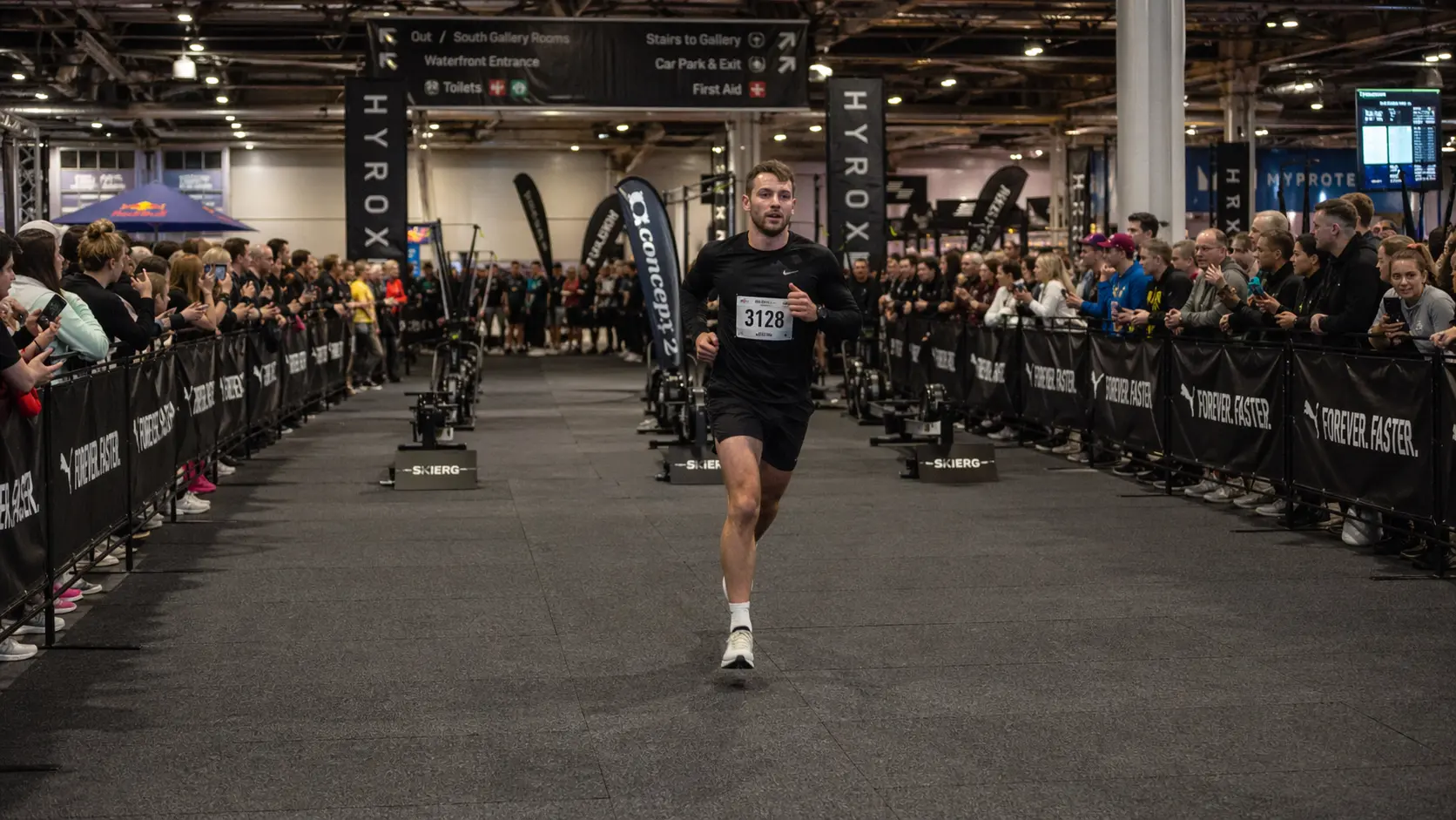 Athlete controlling HYROX running pace during transition run inside exhibition hall