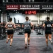 Women running toward the HYROX finish line — HYROX average finishing time for women