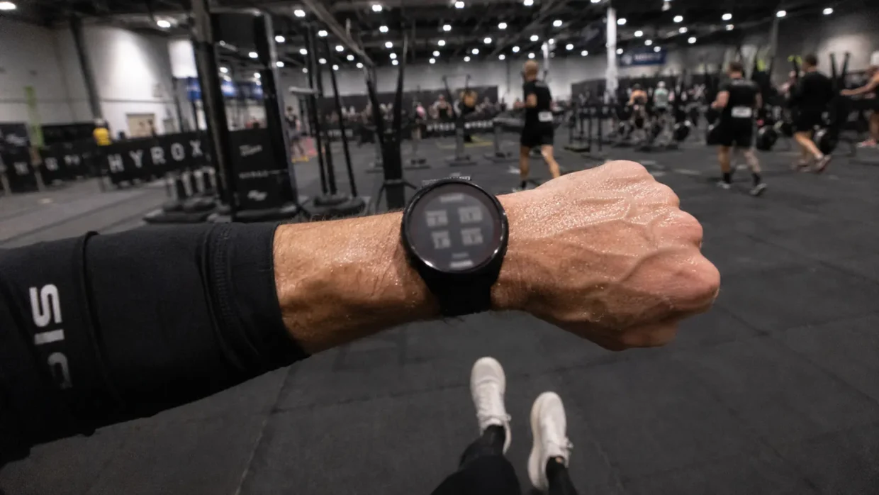 Best watch for HYROX — first-person POV of athlete checking GPS watch during indoor race