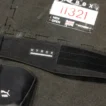 Black nylon lifting belt for HYROX laid on rubber race floor tiles next to a race bib and knee sleevesVous avez dit : Ca correspond bien?