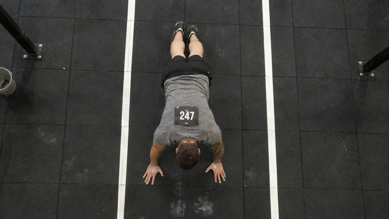 how to train burpee broad jumps for HYROX — athlete in plank position on rubber floor during station 4