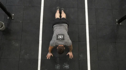 how to train burpee broad jumps for HYROX — athlete in plank position on rubber floor during station 4