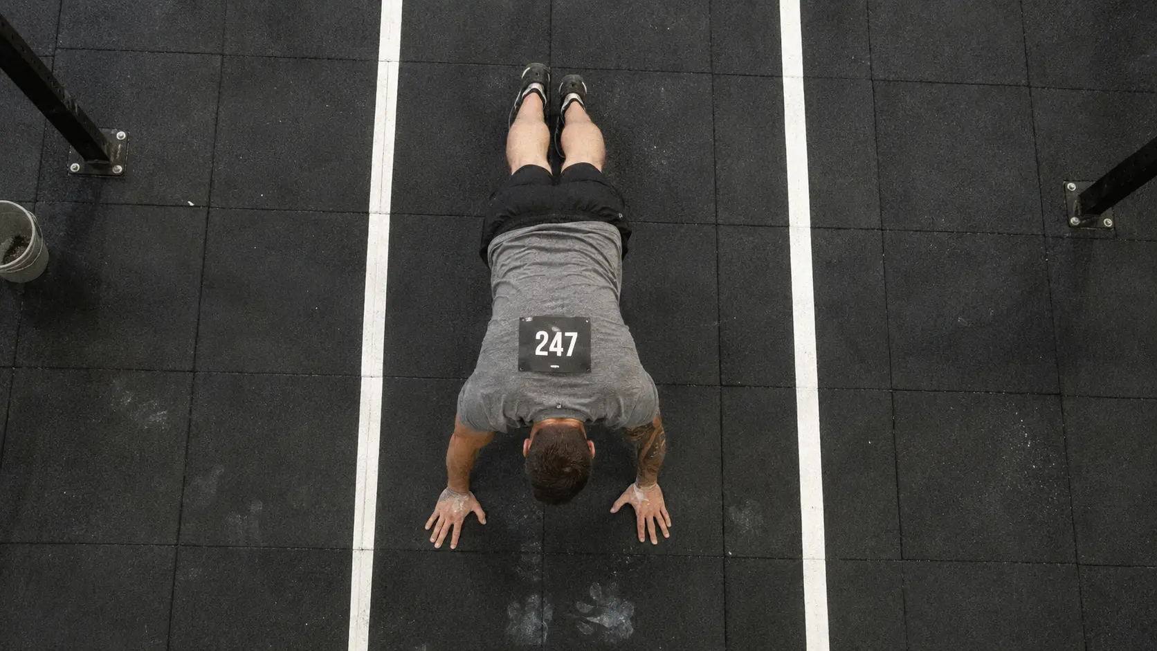 how to train burpee broad jumps for HYROX — athlete in plank position on rubber floor during station 4