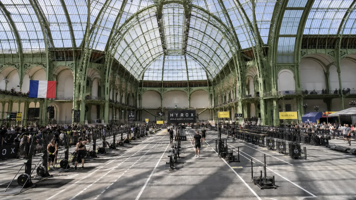 HYROX cost in France — Paris Grand Palais race venue with athletes competing across sled pull lanes under the iconic glass roof