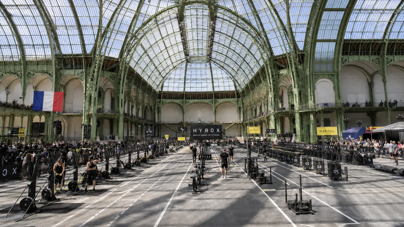 HYROX cost in France — Paris Grand Palais race venue with athletes competing across sled pull lanes under the iconic glass roof