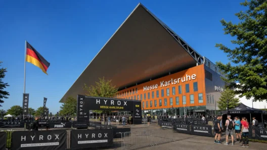 HYROX cost in Germany — Messe Karlsruhe venue exterior with German flag and athletes gathering before race day