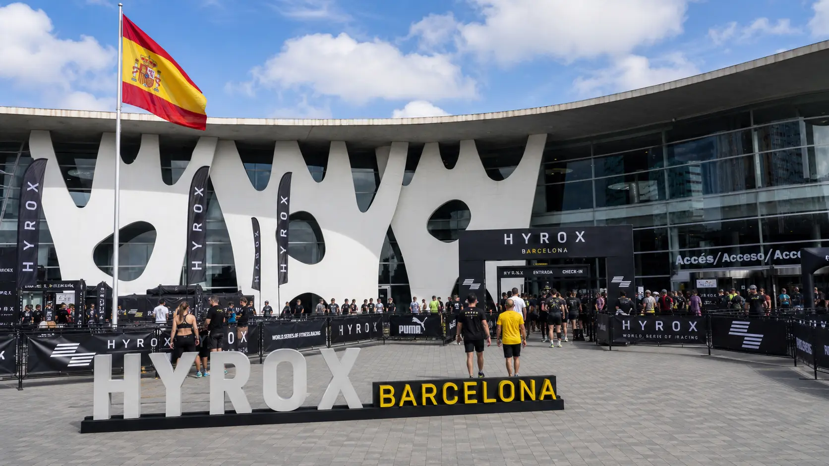 HYROX cost in Spain — HYROX Barcelona venue entrance at Fira Barcelona with Spanish flag and athletes arriving on race day