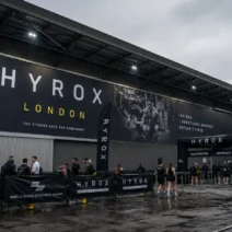 HYROX London 2026 — athletes queuing at the ExCeL London venue entrance on race day, HYROX London signage visible