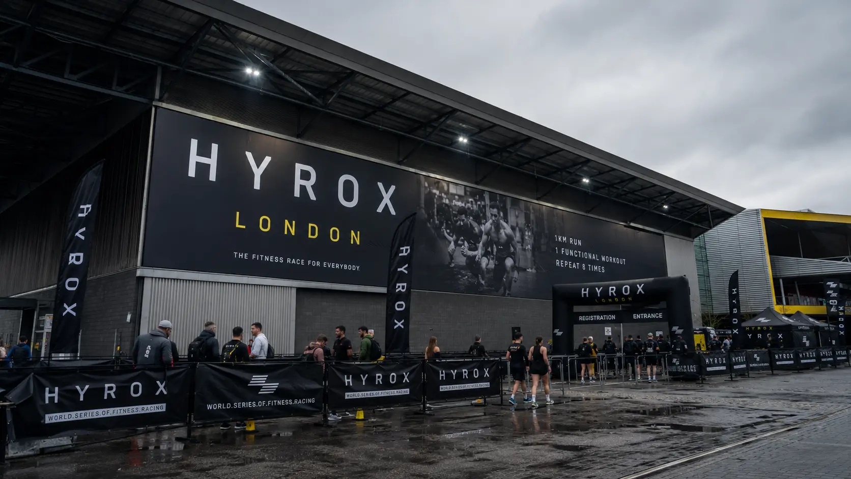 HYROX London 2026 — athletes queuing at the ExCeL London venue entrance on race day, HYROX London signage visible