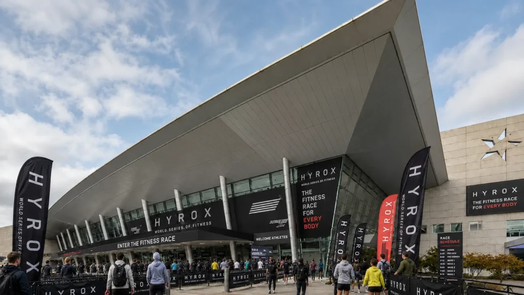 HYROX World Series of Fitness venue exterior with athletes arriving on race day under daytime sky