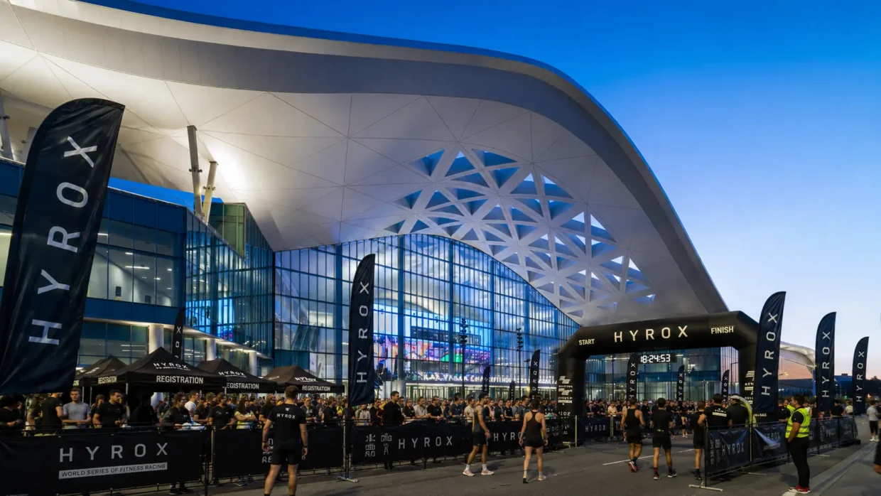 Athletes at the HYROX start/finish arch outside the Las Vegas Convention Center at dusk