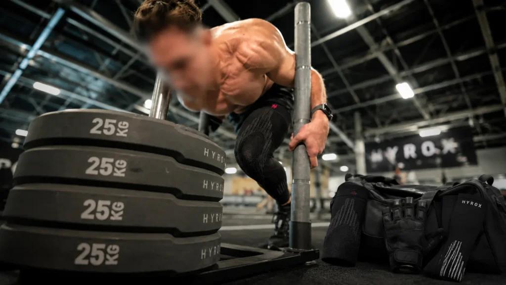 Athlete performing a HYROX sled push in compression leg wear, illustrating a best HYROX equipment 2026 setup