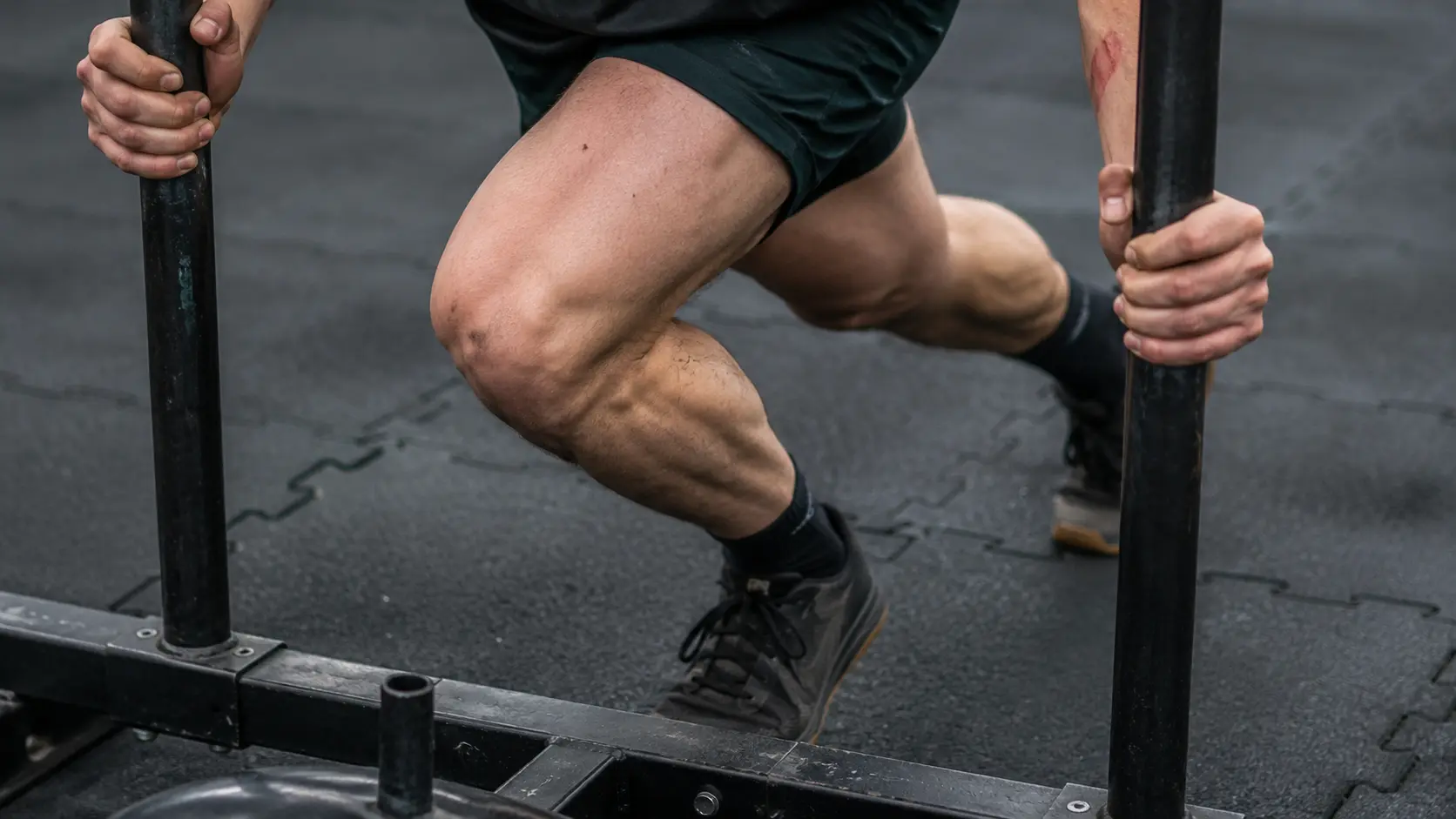 HYROX injury prevention: close-up of knee and leg position during a sled push to avoid strain