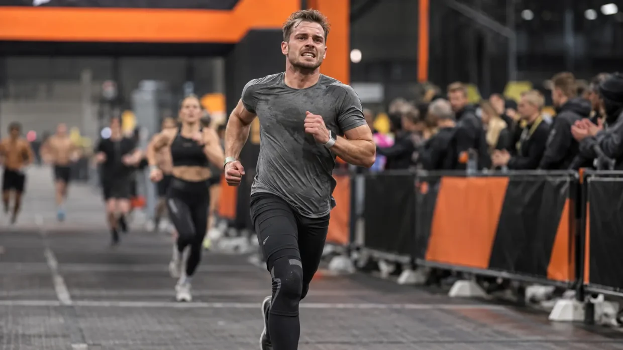 Man running toward the HYROX finish line — HYROX average finishing time for men