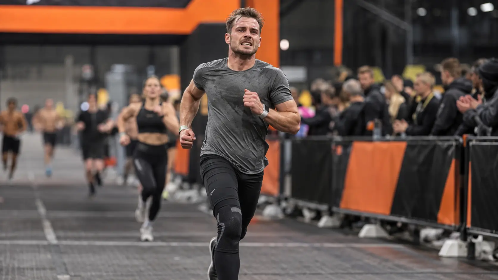 Man running toward the HYROX finish line — HYROX average finishing time for men