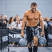 Athlete carrying heavy kettlebells during farmers carry for HYROX training