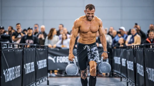 Athlete carrying heavy kettlebells during farmers carry for HYROX training