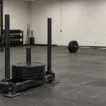 HYROX XENOM deal: a HYROX sled and a loaded barbell on a gray gym floor