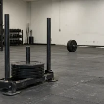 HYROX XENOM deal: a HYROX sled and a loaded barbell on a gray gym floor